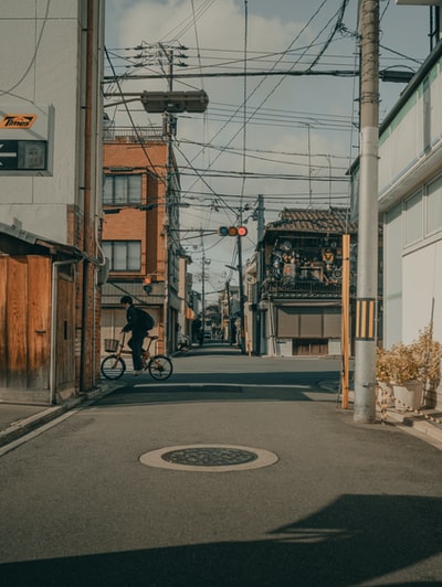 白天，身穿黑色夹克的男子在路上骑自行车
